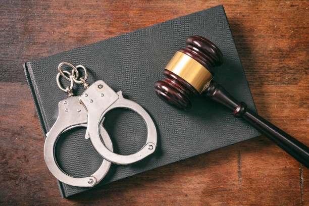 Handcuffs, gavel on book on a wooden background,